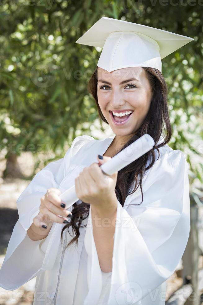 graduando-se menina de raça mista em boné e vestido com diploma foto