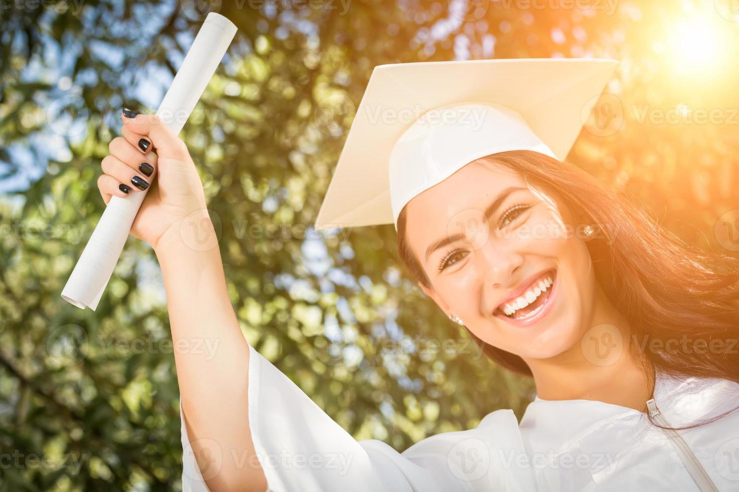 graduando-se menina de raça mista em boné e vestido com diploma foto