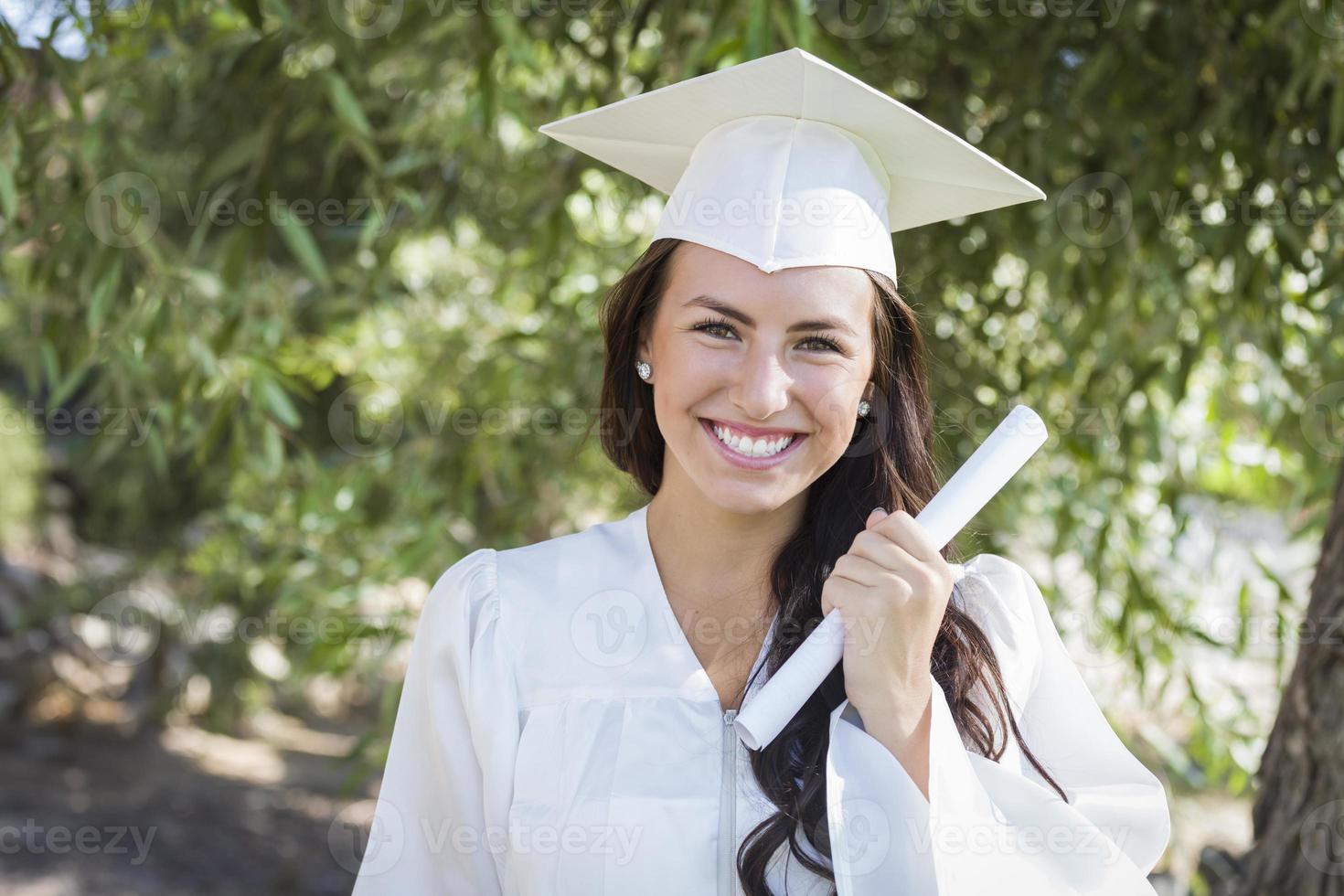 graduando-se menina de raça mista em boné e vestido com diploma foto