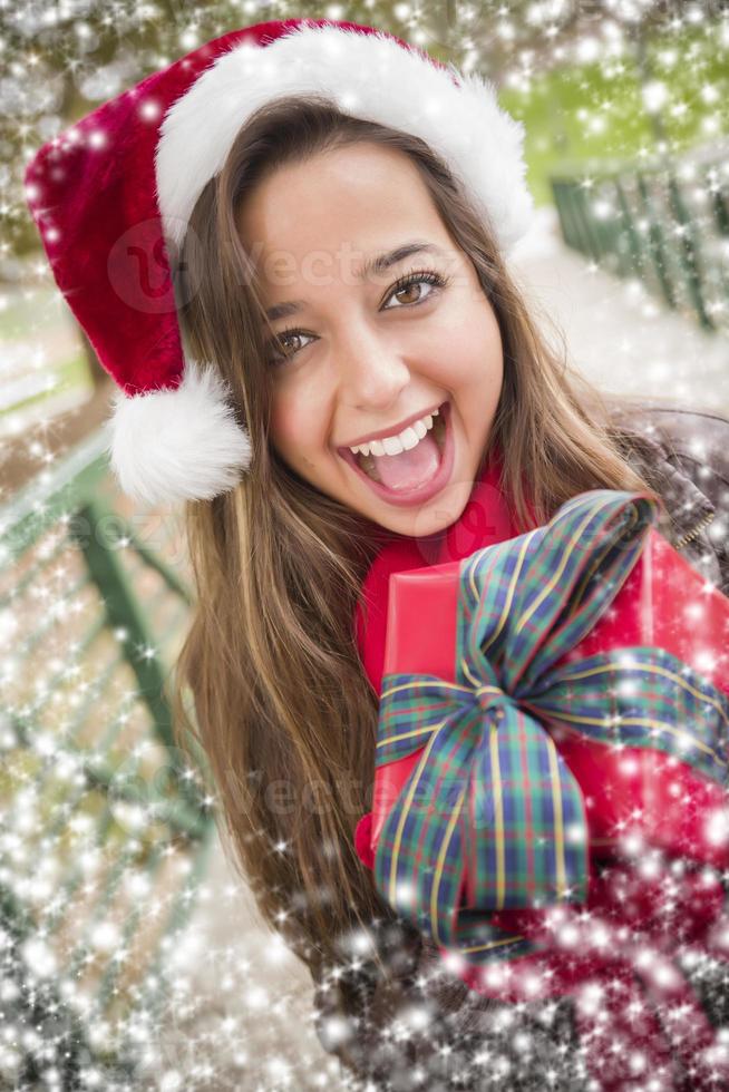 linda mulher usando um chapéu de Papai Noel com presente embrulhado foto