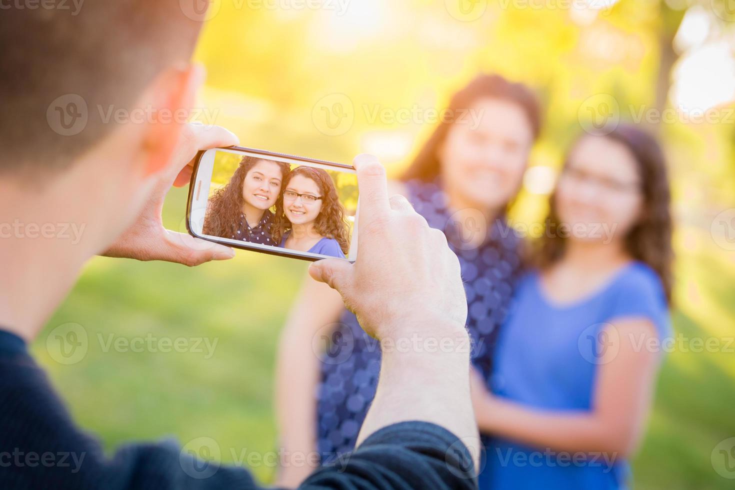 pai hispânico tirando foto de mãe e filha com telefone celular