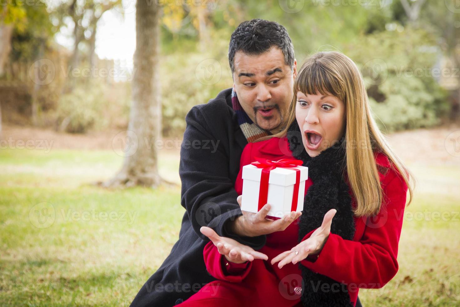 casal de raça mista compartilhando presente de natal ou dia dos namorados lá fora foto