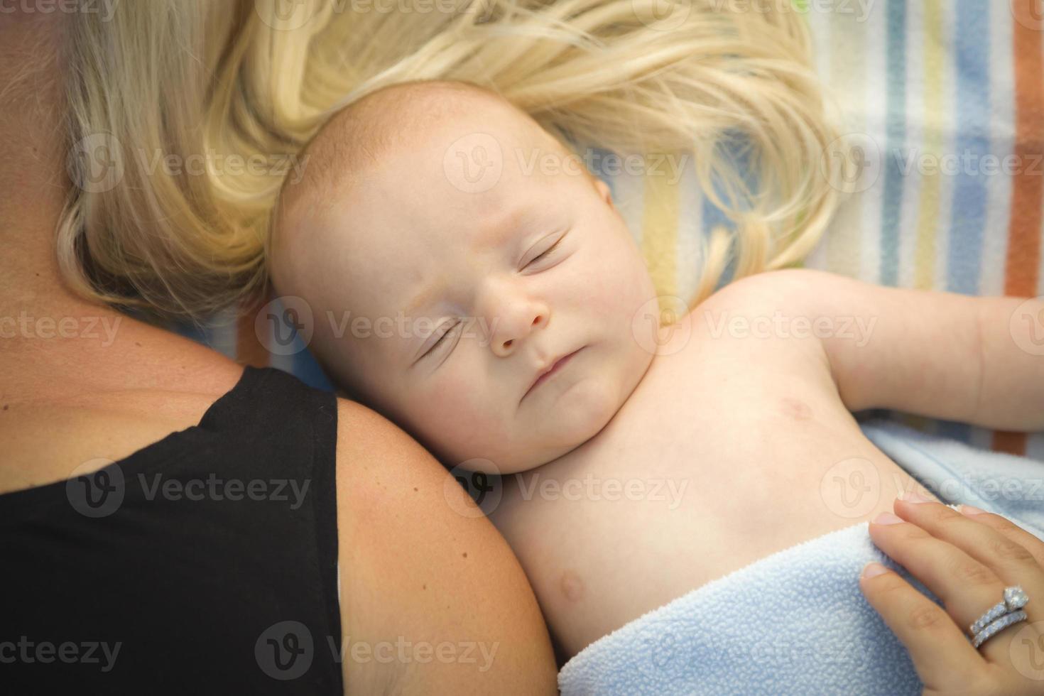 menino bonito deitado ao lado de sua mãe no cobertor foto