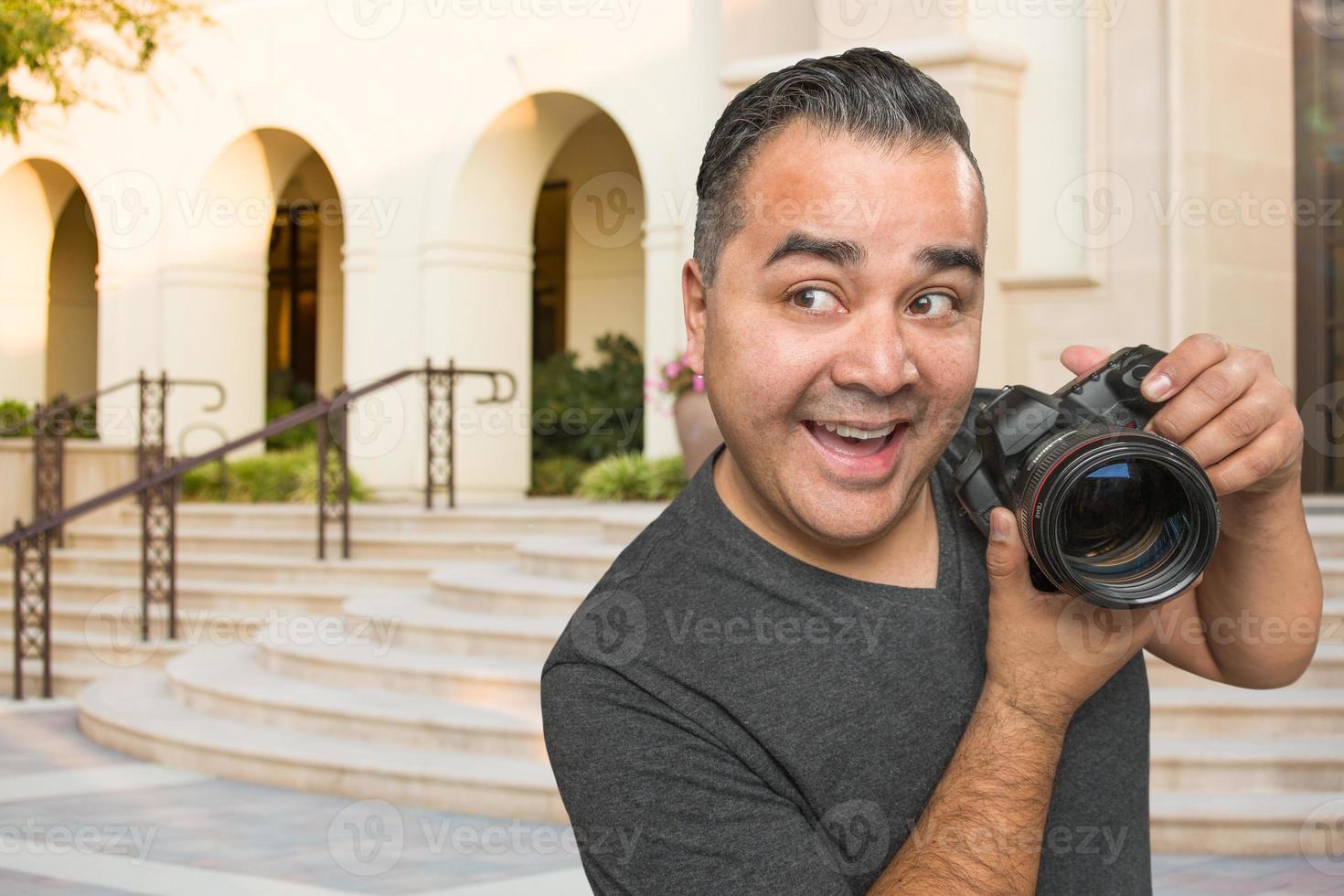 jovem fotógrafo masculino hispânico com câmera dslr ao ar livre foto