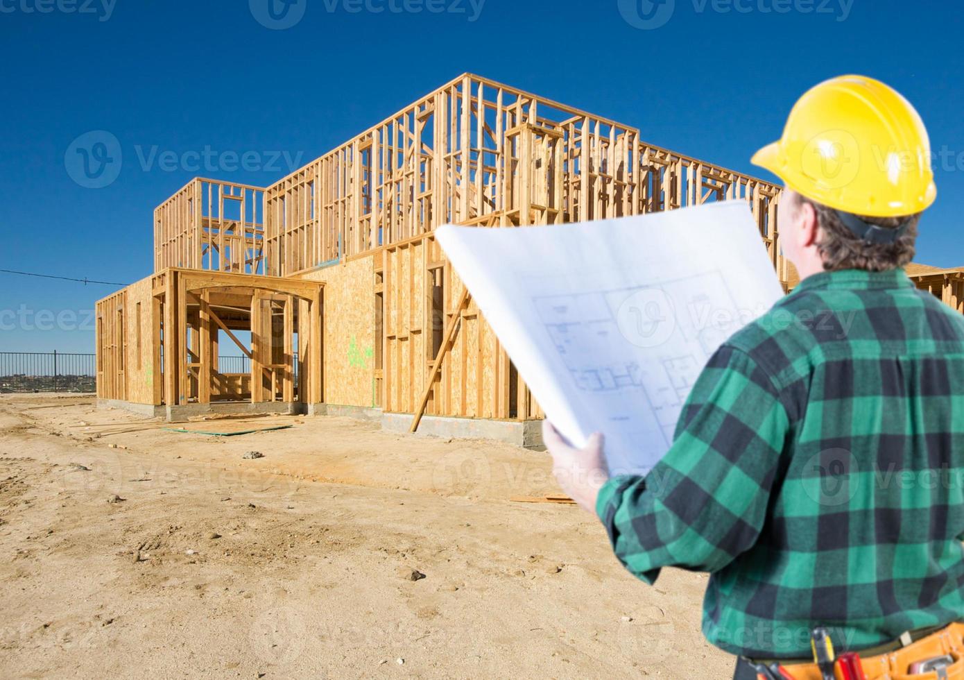 empreiteiro com planos e capacete olhando para o novo enquadramento da casa no canteiro de obras. foto