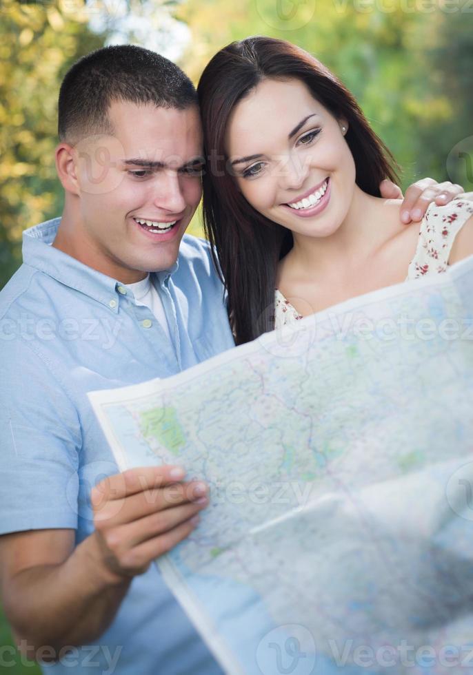 casal de raça mista olhando por cima do mapa do lado de fora juntos foto