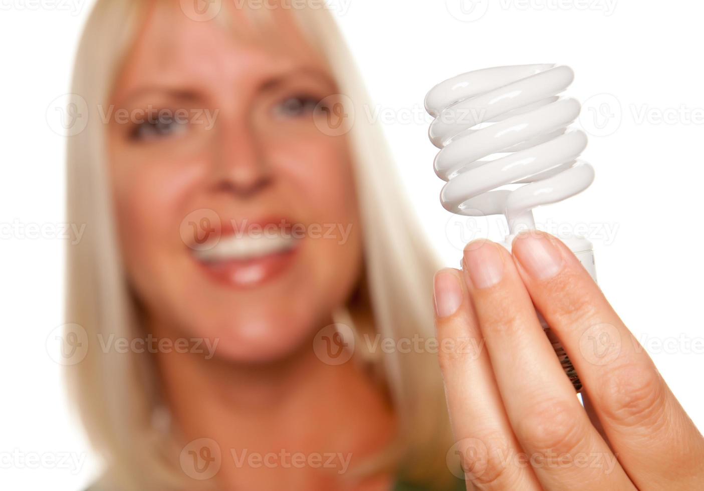 mulher loira atraente segura lâmpada economizadora de energia foto