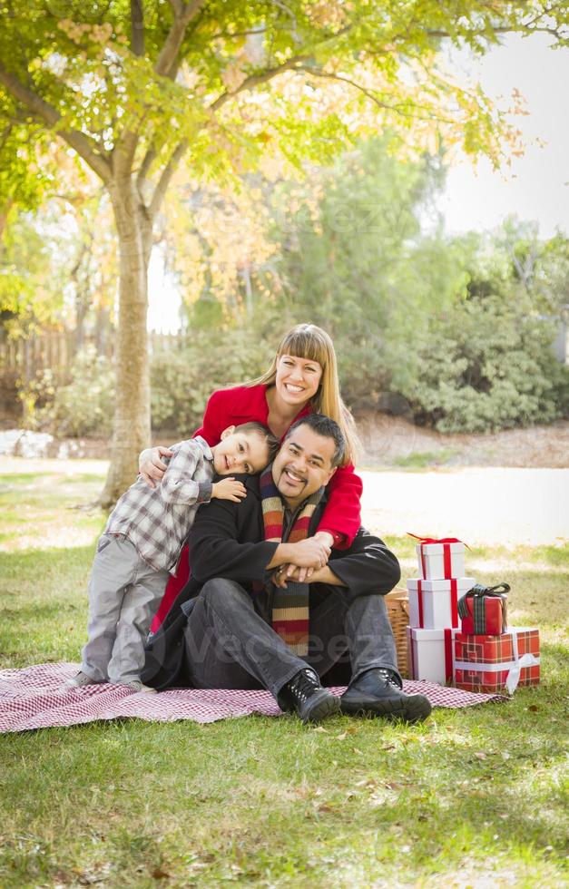 família de raça mista desfrutando de presentes de natal no parque juntos foto