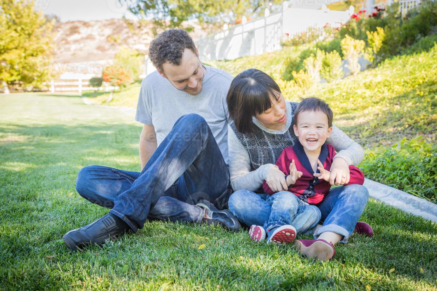 família de raça mista feliz se divertindo lá fora na grama foto