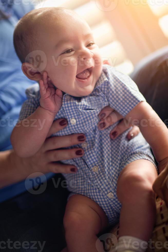 casal de raça mista feliz curtindo seu filho recém-nascido à luz da janela. foto