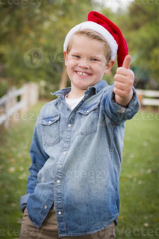 menino vestindo roupas de férias dando um sinal de positivo lá fora foto