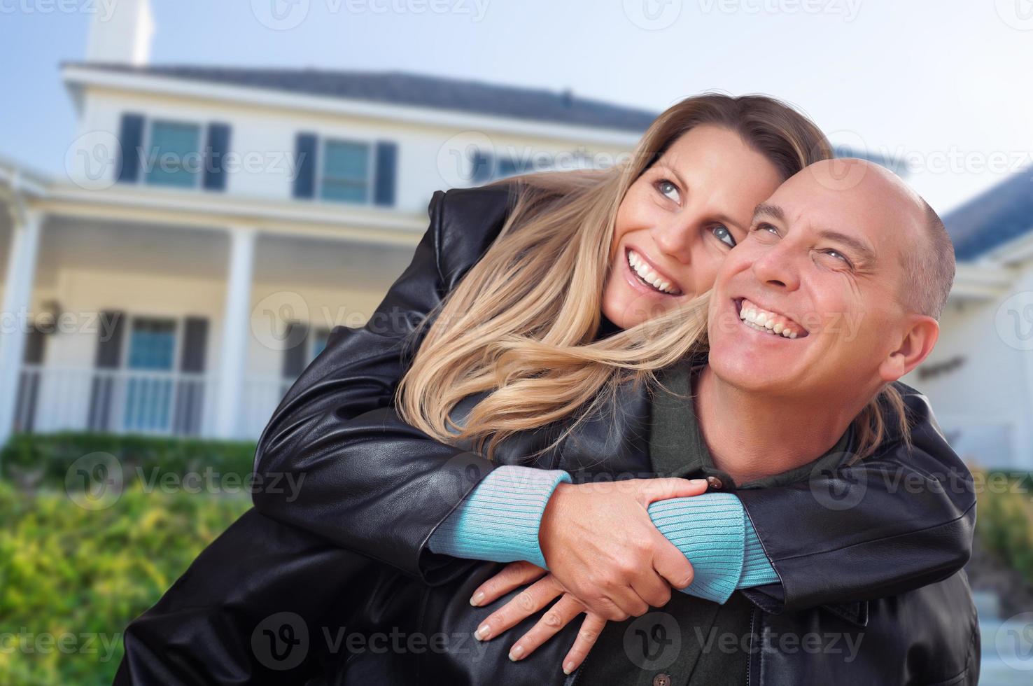 casal feliz abraçando na frente da linda casa foto