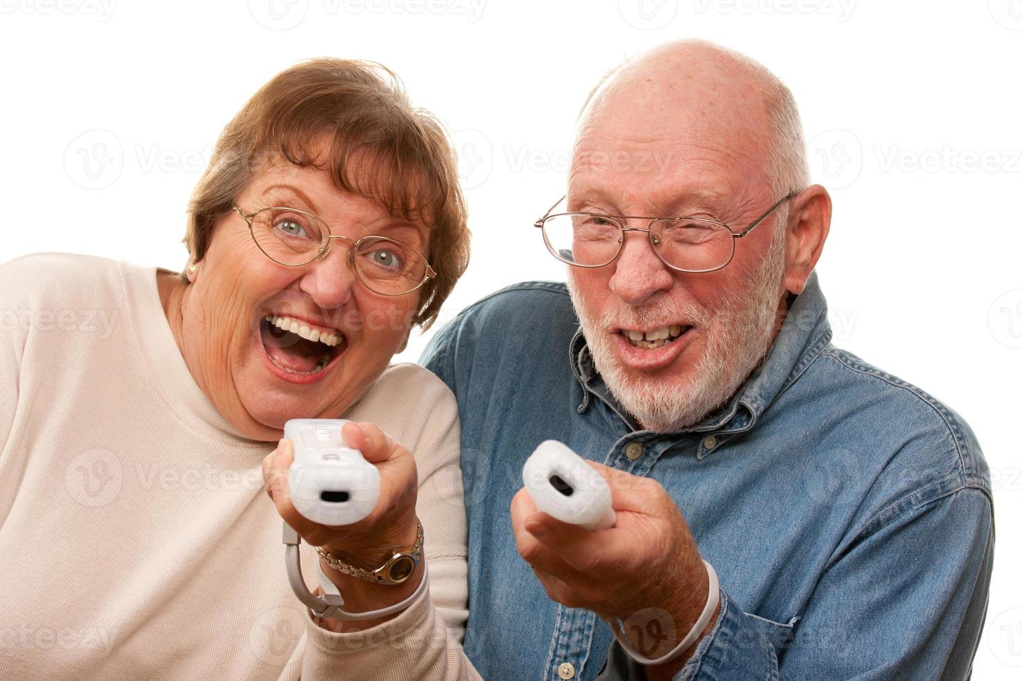 casal sênior feliz joga videogame com controles remotos foto