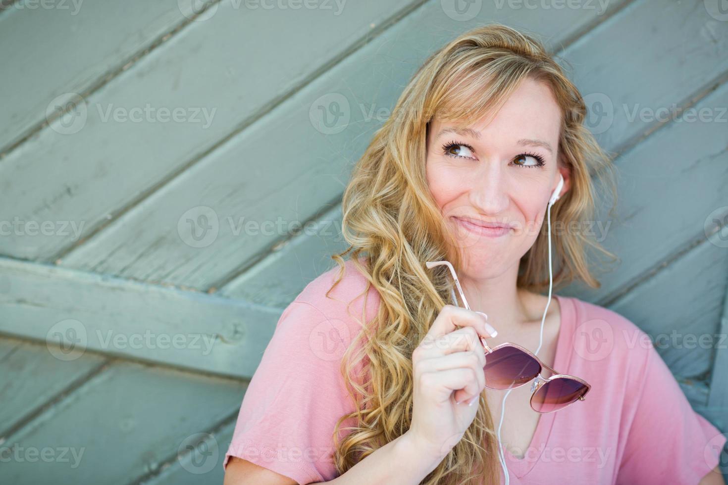 retrato ao ar livre de jovem adulta de olhos castanhos com óculos escuros e fones de ouvido. foto