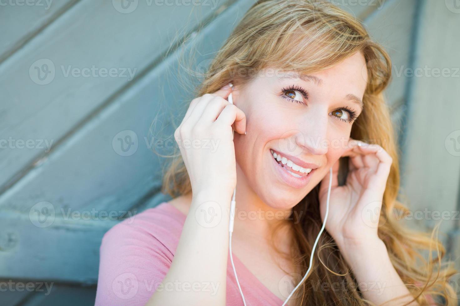 retrato ao ar livre de jovem adulta de olhos castanhos ouvindo música com fones de ouvido. foto