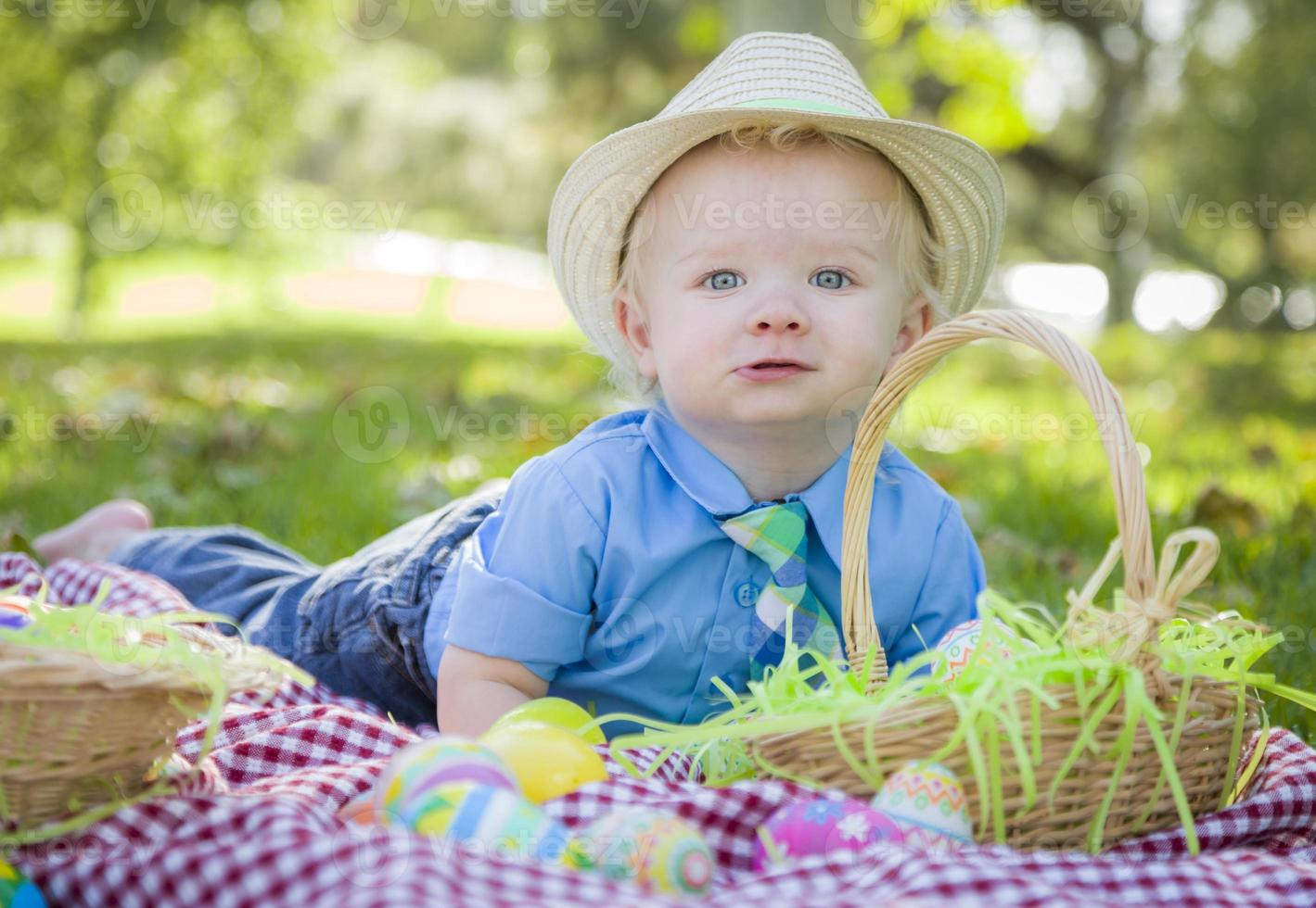 menino bonitinho sorri com ovos de páscoa ao seu redor foto