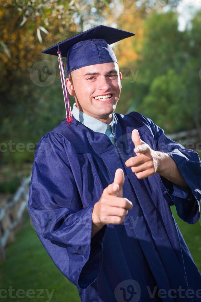 feliz graduado masculino bonito em boné e vestido lá fora. foto