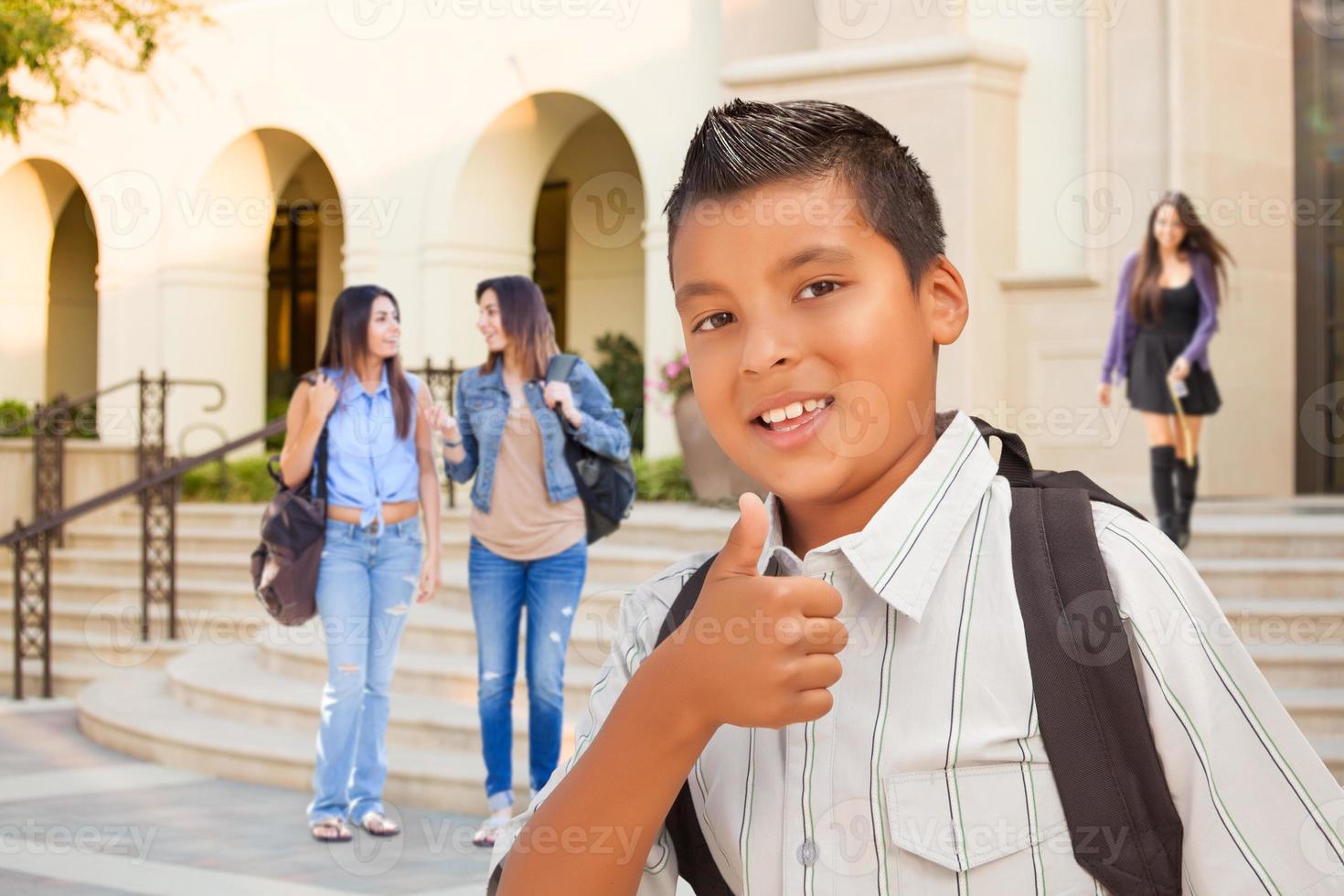 menino jovem estudante latino-americano com polegares para cima no campus foto