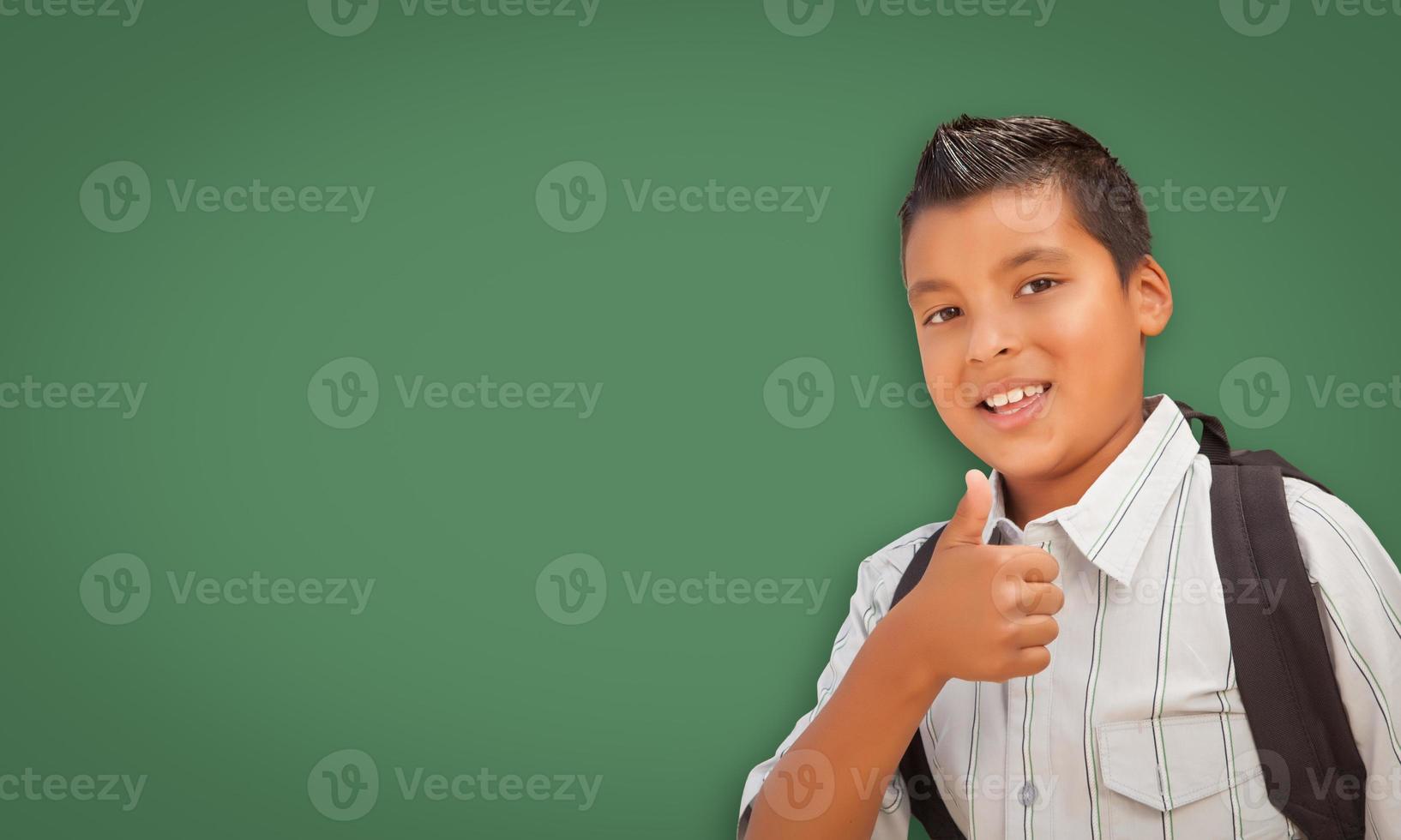 menino bonito hispânico na frente do quadro de giz em branco foto