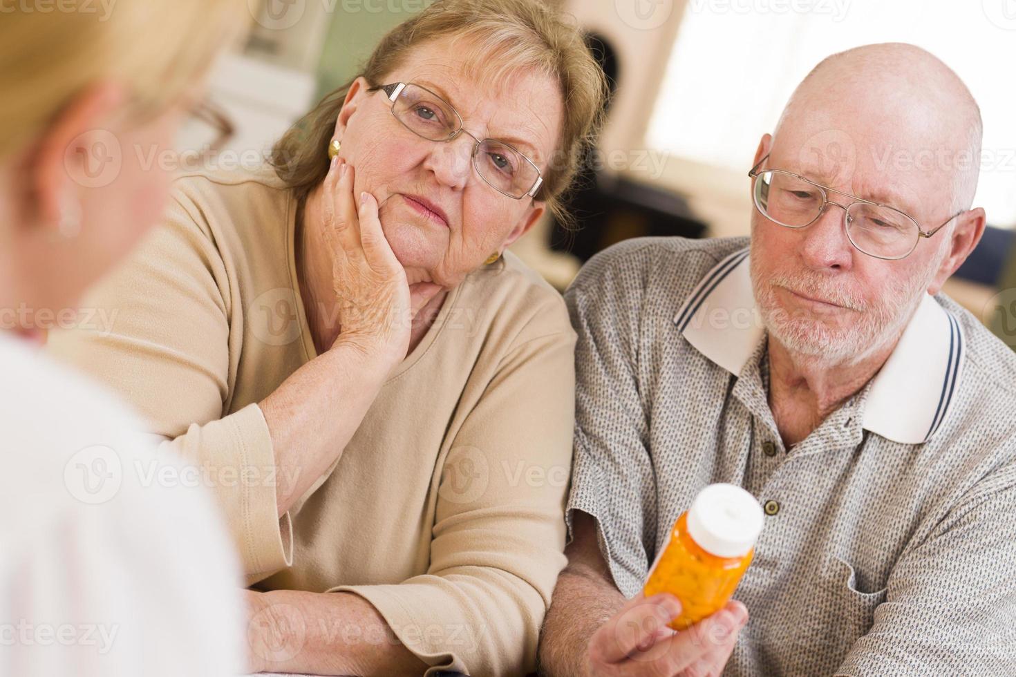 médico ou enfermeira explicando medicamentos prescritos para casal de idosos foto