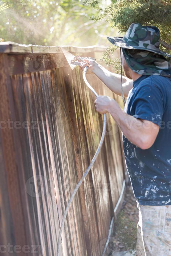 pintor profissional pulverizando cerca de quintal com mancha foto