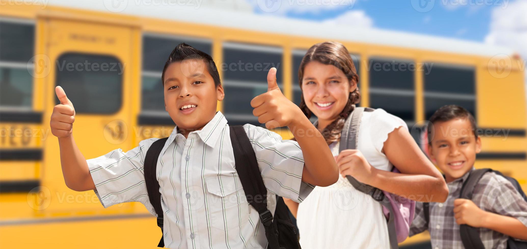 jovens hispânicos meninos e menina andando perto de ônibus escolar foto
