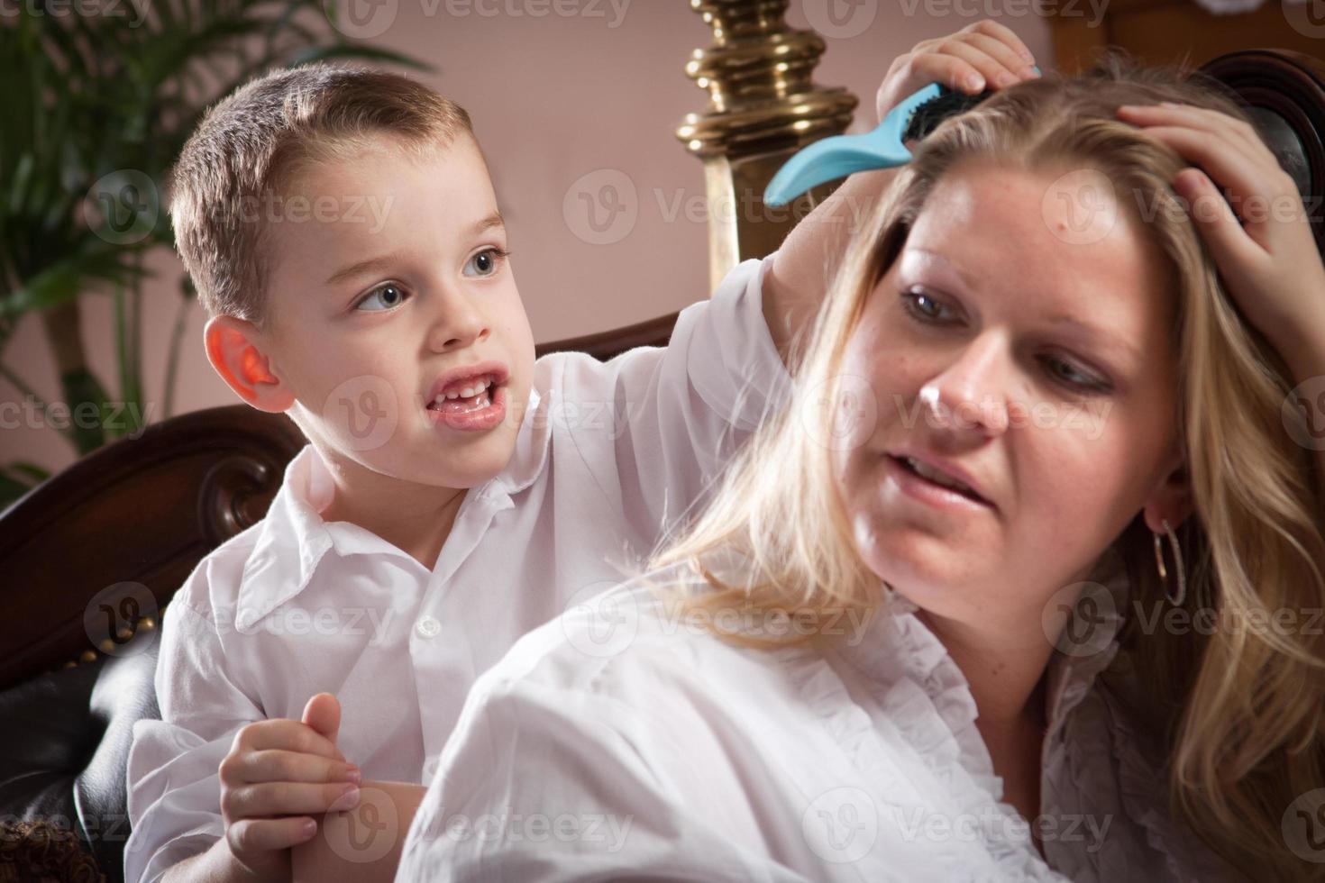 lindo filho escovando o cabelo de sua mãe foto