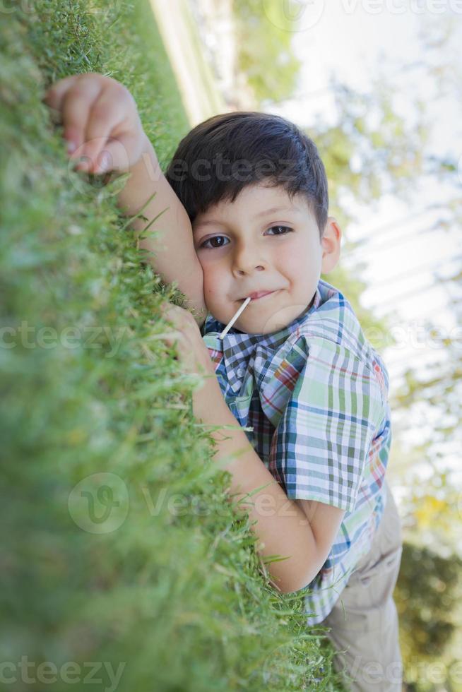 menino desfrutando de seu pirulito ao ar livre deitado na grama foto