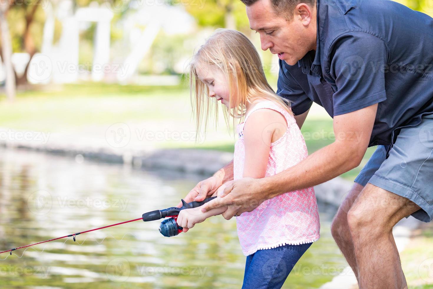 jovem caucasiano pai e filha se divertindo pescando no lago foto