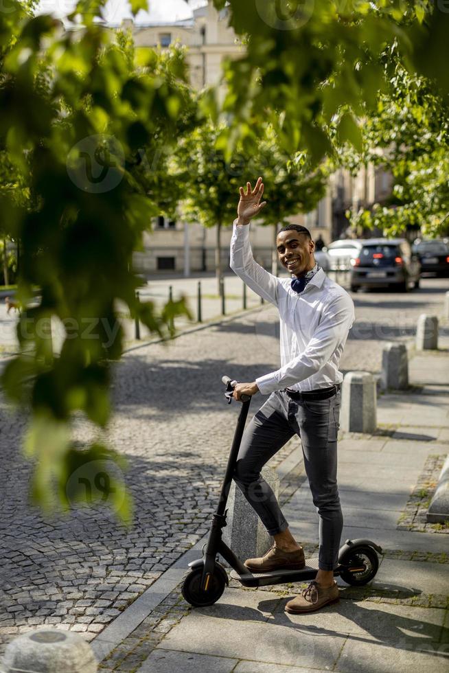 jovem afro-americano usando scooter elétrico em uma rua foto