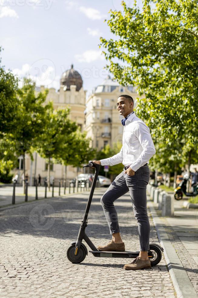 jovem afro-americano usando scooter elétrico em uma rua foto