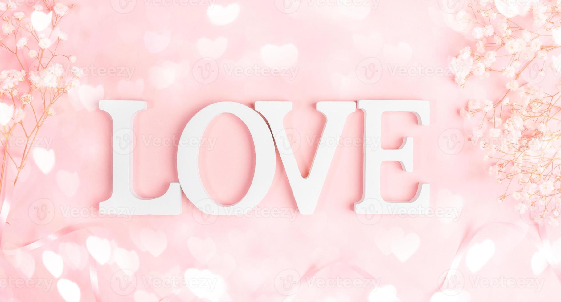 letras brancas amam com moldura de gipsofila branco suave em rosa pastel com corações de luzes de bokeh. foto