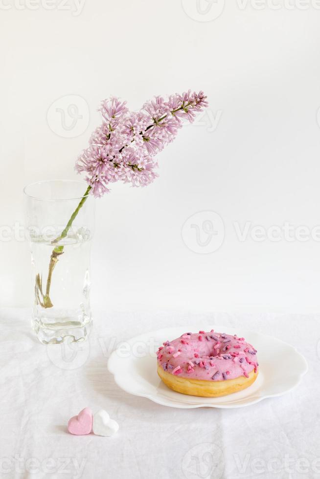 natureza morta moderna mínima com galho lilás e rosquinha em fundo branco. foto