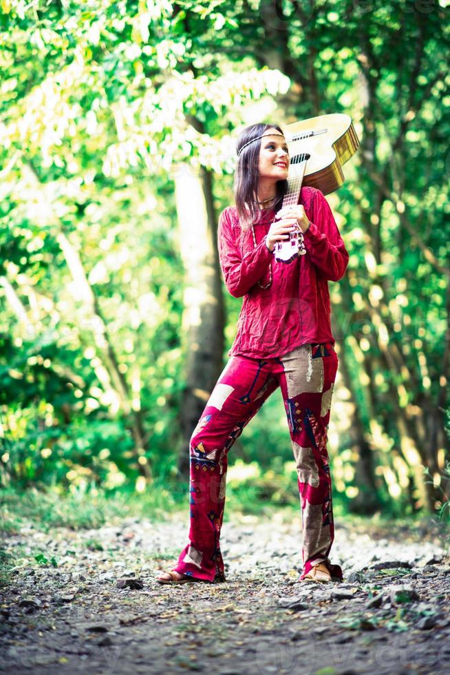 garota hippie com a guitarra na floresta foto