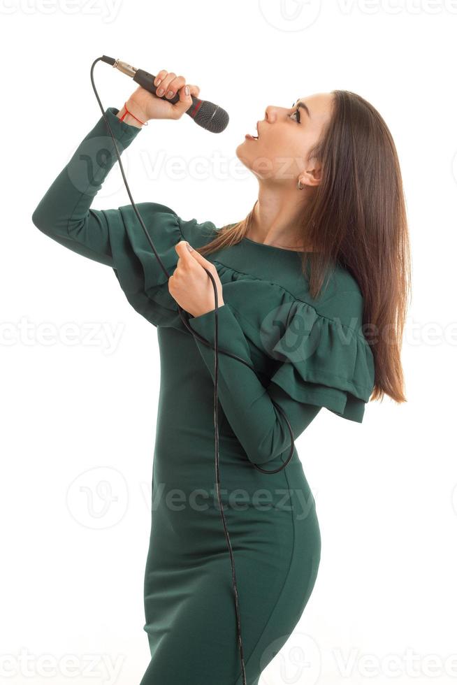 linda mulher de vestido verde cantando um karaokê com microfone foto