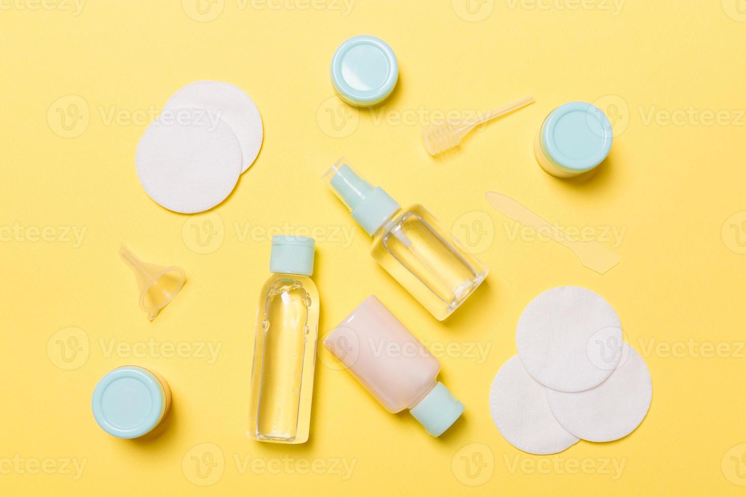 vista superior de meios para frascos de cuidados faciais e frascos de tônico, água de limpeza micelar, creme, almofadas de algodão em fundo amarelo. conceito de cuidados corporais com cpace vazio para suas ideias foto