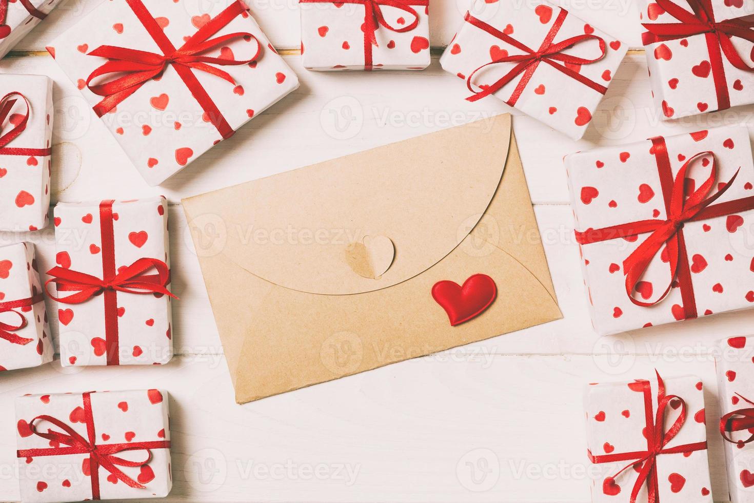 correio de envelope com coração vermelho e caixa de presente sobre fundo tonificado vintage de madeira. cartão de dia dos namorados, design de conceito de saudação de amor ou casamento foto