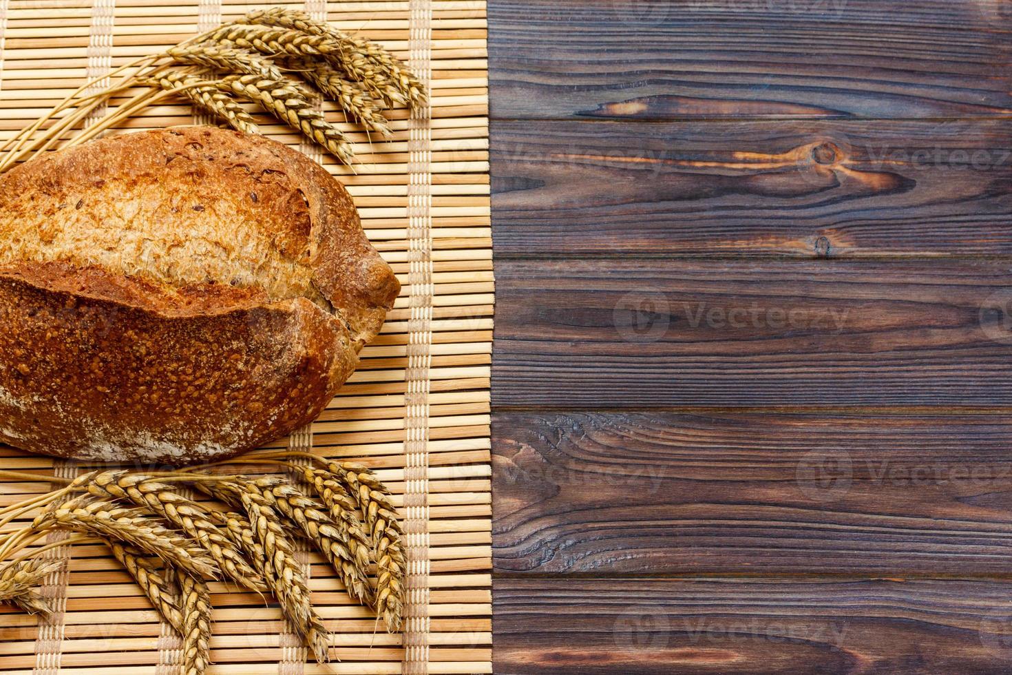 pão rústico e trigo em uma velha mesa de madeira de tábuas vintage. plano de fundo com espaço de texto livre foto