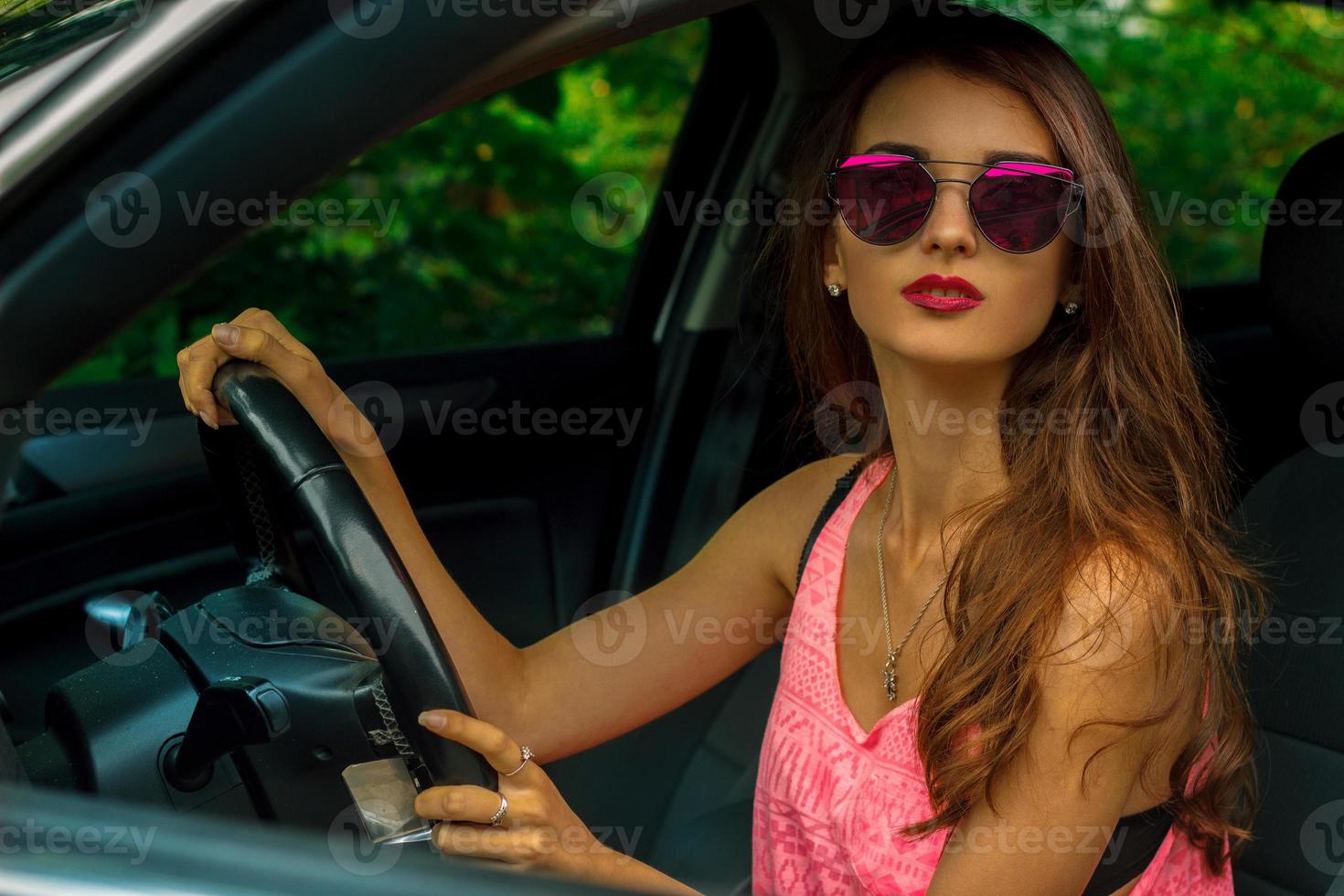 jovem morena bonita senta-se ao volante de um carro foto