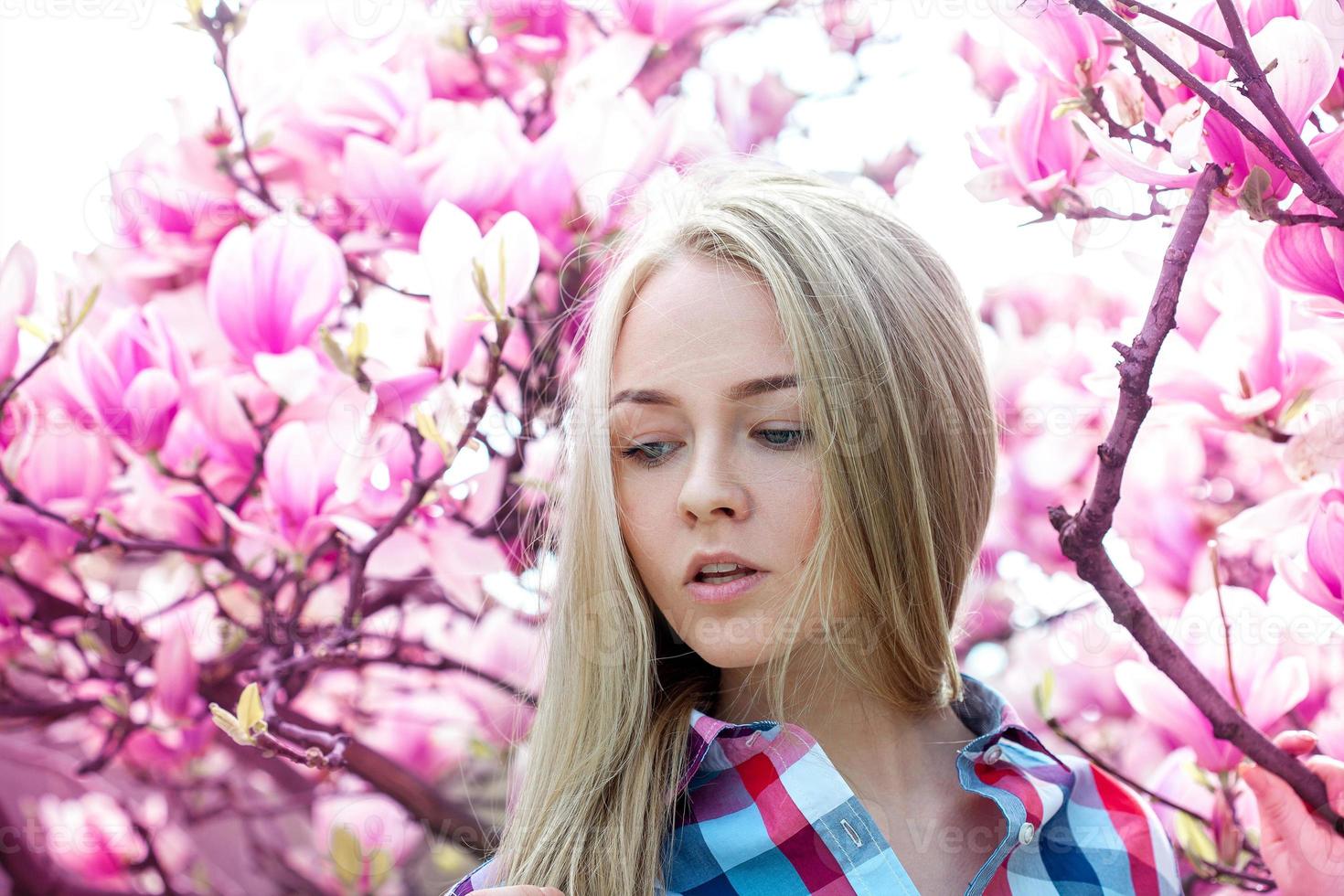 retrato sensual da beleza loira com flores cor de rosa na árvore por trás foto