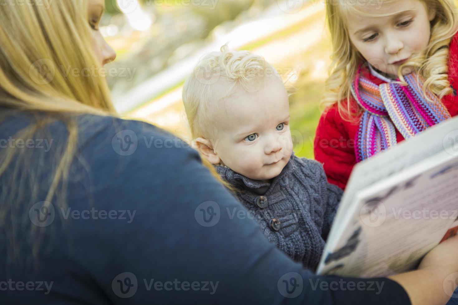 mãe lendo um livro para seus dois filhos loiros adoráveis foto