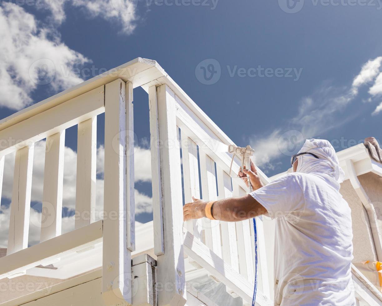pintor de casa pintando com spray um deck de uma casa foto
