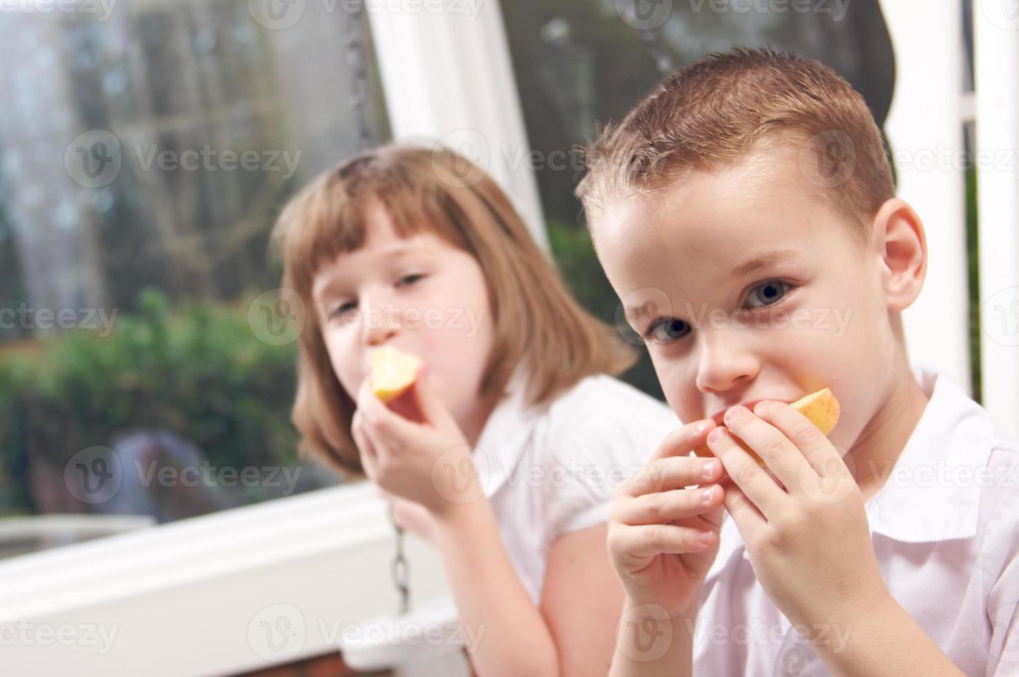 irmã e irmão comendo uma maçã foto