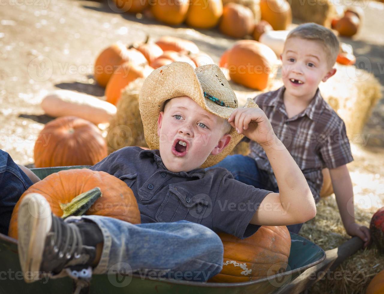 dois meninos brincando no carrinho de mão no canteiro de abóboras foto