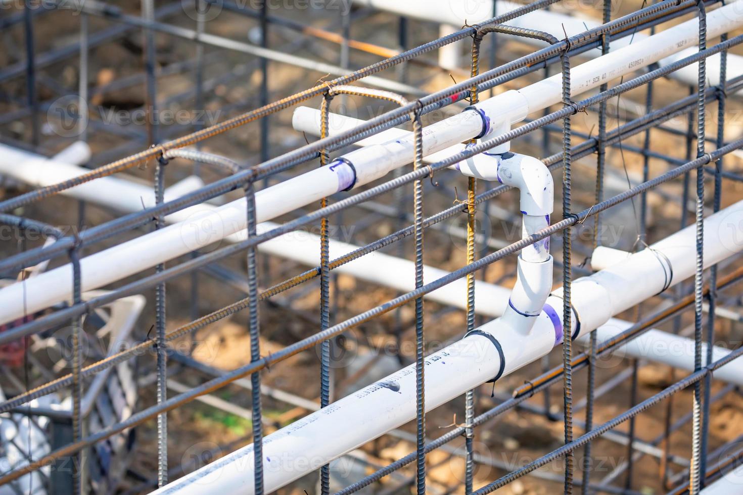 tubos de encanamento de pvc recém-instalados e configuração de vergalhões de aço no canteiro de obras foto
