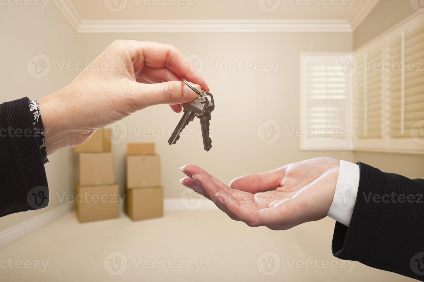 mulher entregando as chaves da casa dentro da sala tan vazia foto