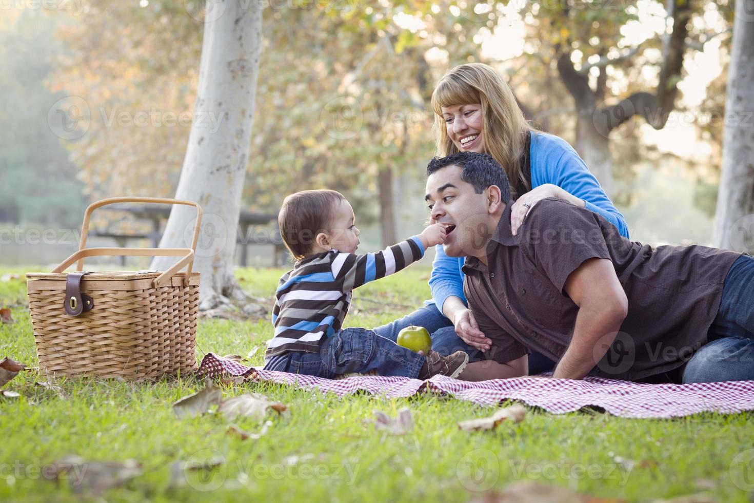 feliz família étnica de raça mista fazendo piquenique no parque foto