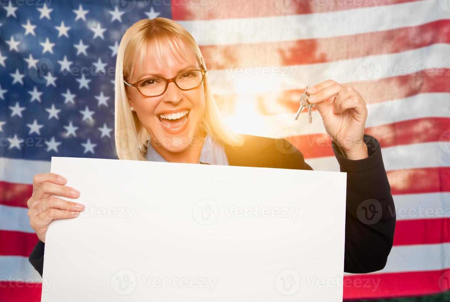 jovem mulher segurando as chaves de casa e sinal em branco na frente da bandeira americana foto