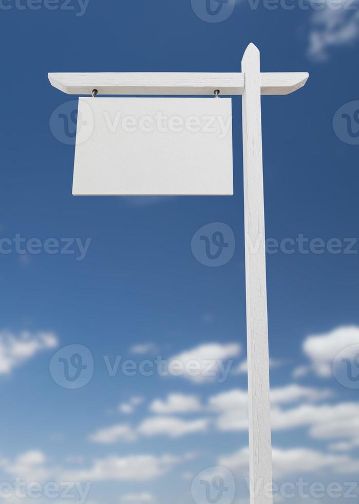 sinal imobiliário em branco sobre um céu azul com nuvens. foto