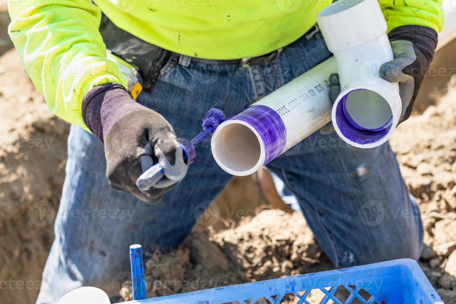 encanador aplicando limpador de cachimbo, primer e cola para tubo de pvc no canteiro de obras foto